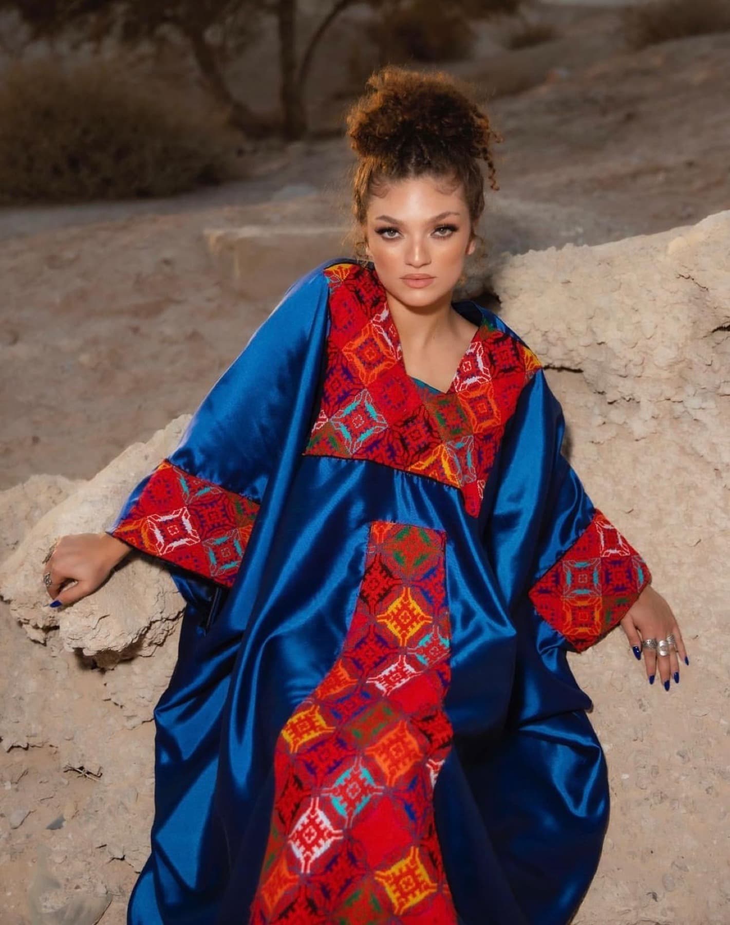 Blue Jafra garment with red embroidery against stone